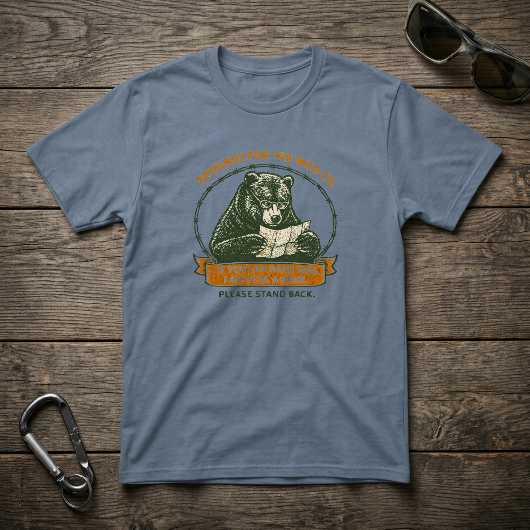 Blue graphic T-shirt by Designed For The Wild Co featuring "I Am Still A Bear" text and a bear illustration on soft garment-dyed fabric.