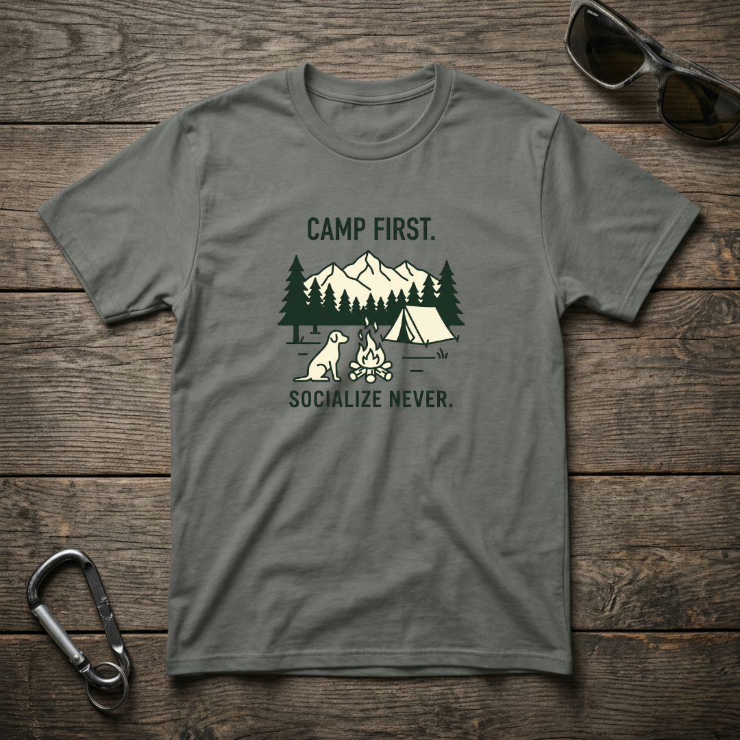 Grey graphic T-shirt from Designed For The Wild Co featuring the "Camp First, Socialize Never" print on soft, garment-dyed fabric.