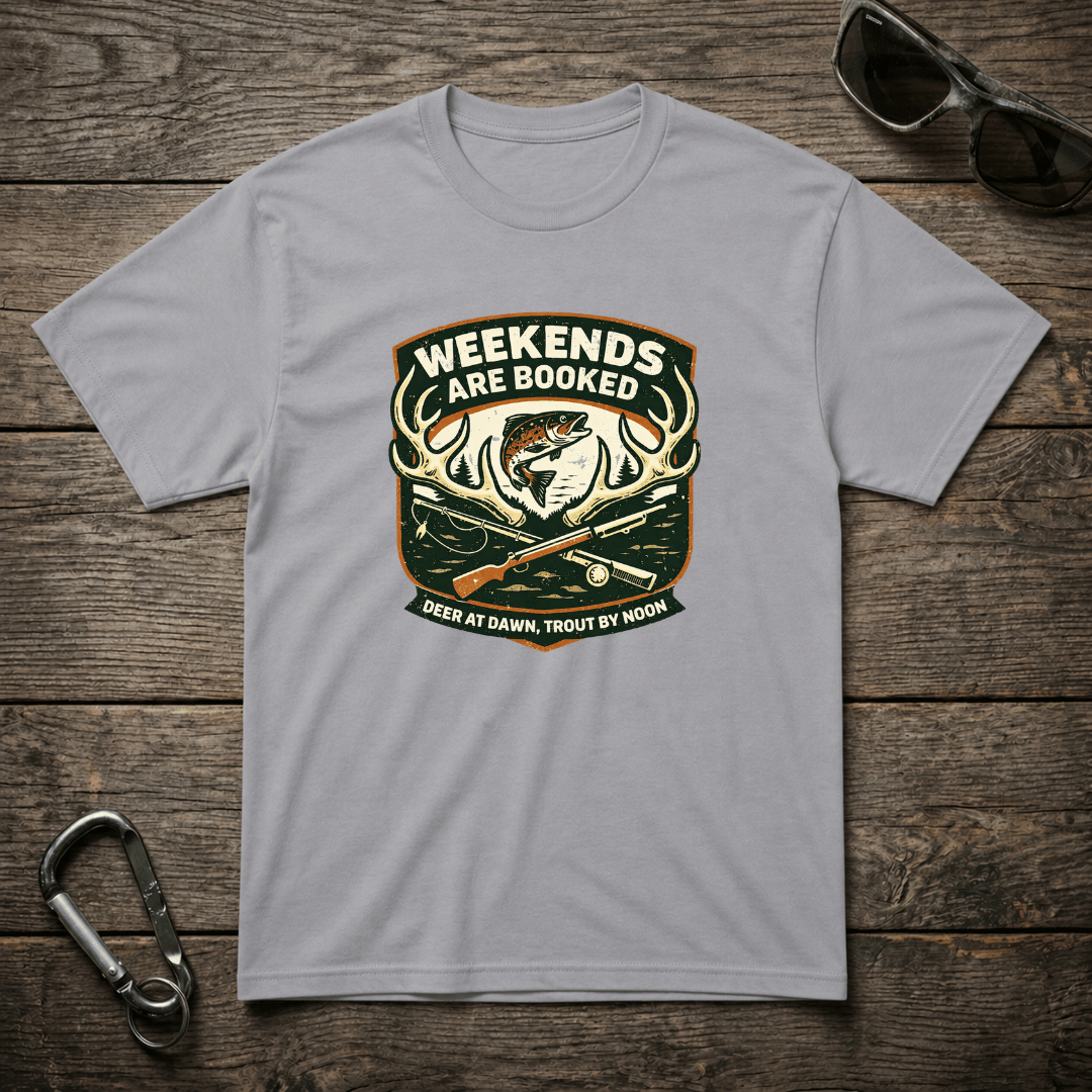 Gray graphic T-shirt from Designed For The Wild Co featuring "Weekends Are Booked Camping" text and outdoor adventure design.