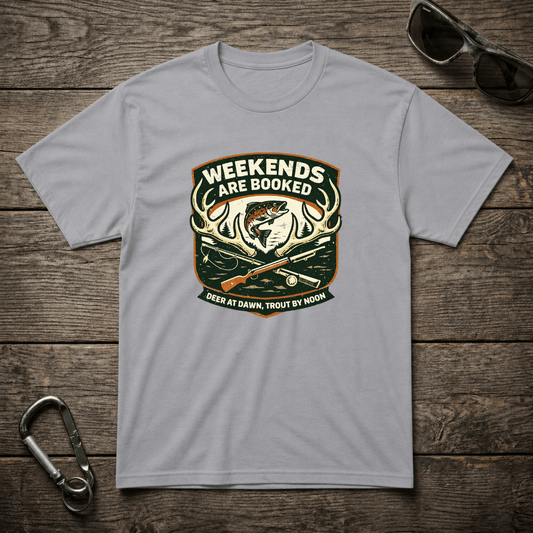 Gray graphic T-shirt from Designed For The Wild Co featuring "Weekends Are Booked Camping" text and outdoor adventure design.