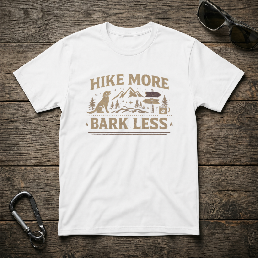 White graphic T-shirt from Designed For The Wild Co with "Hike More, Bark Less" slogan and nature-inspired design.