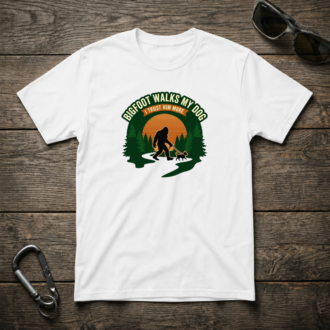 White graphic T-shirt from Designed For The Wild Co featuring a Bigfoot walking my dog illustration on soft, comfortable fabric.
