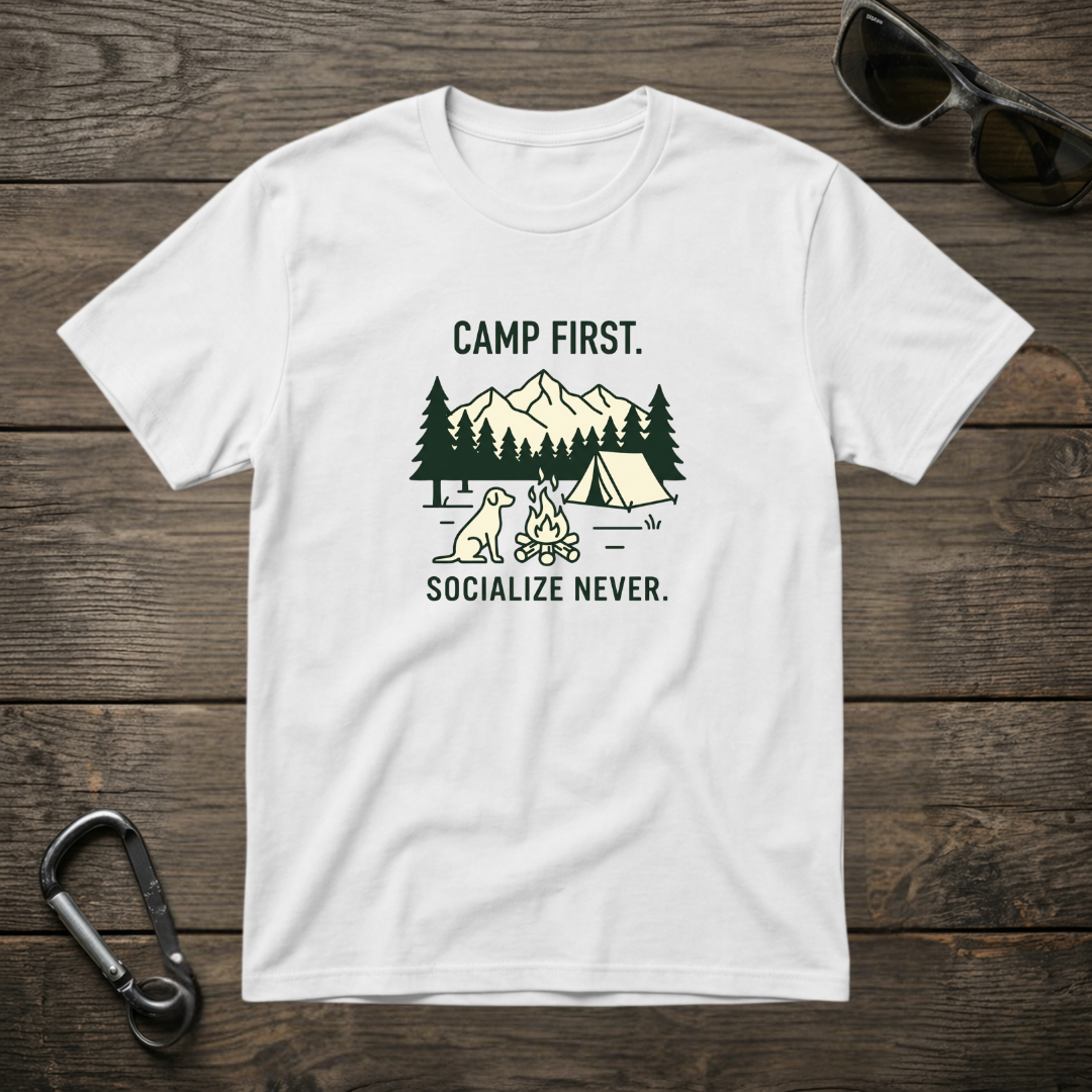 White graphic T-shirt by Designed For The Wild Co with "Camp First, Socialize Never" slogan, garment-dyed cotton tee.